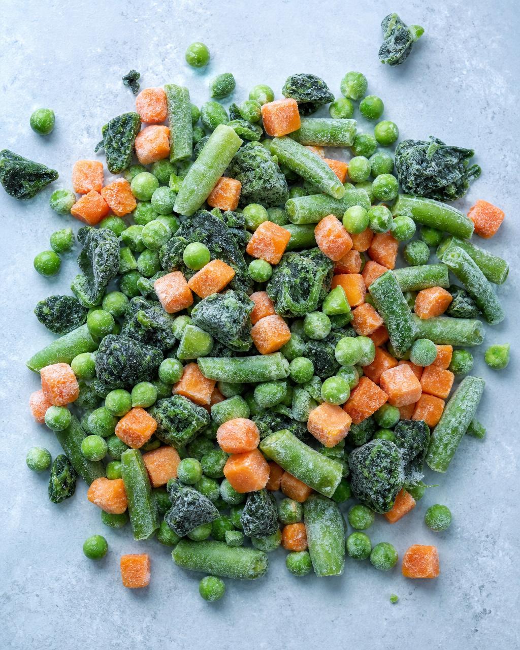 Frosted frozen peas, carrots, green beans and spinach with ice crystals